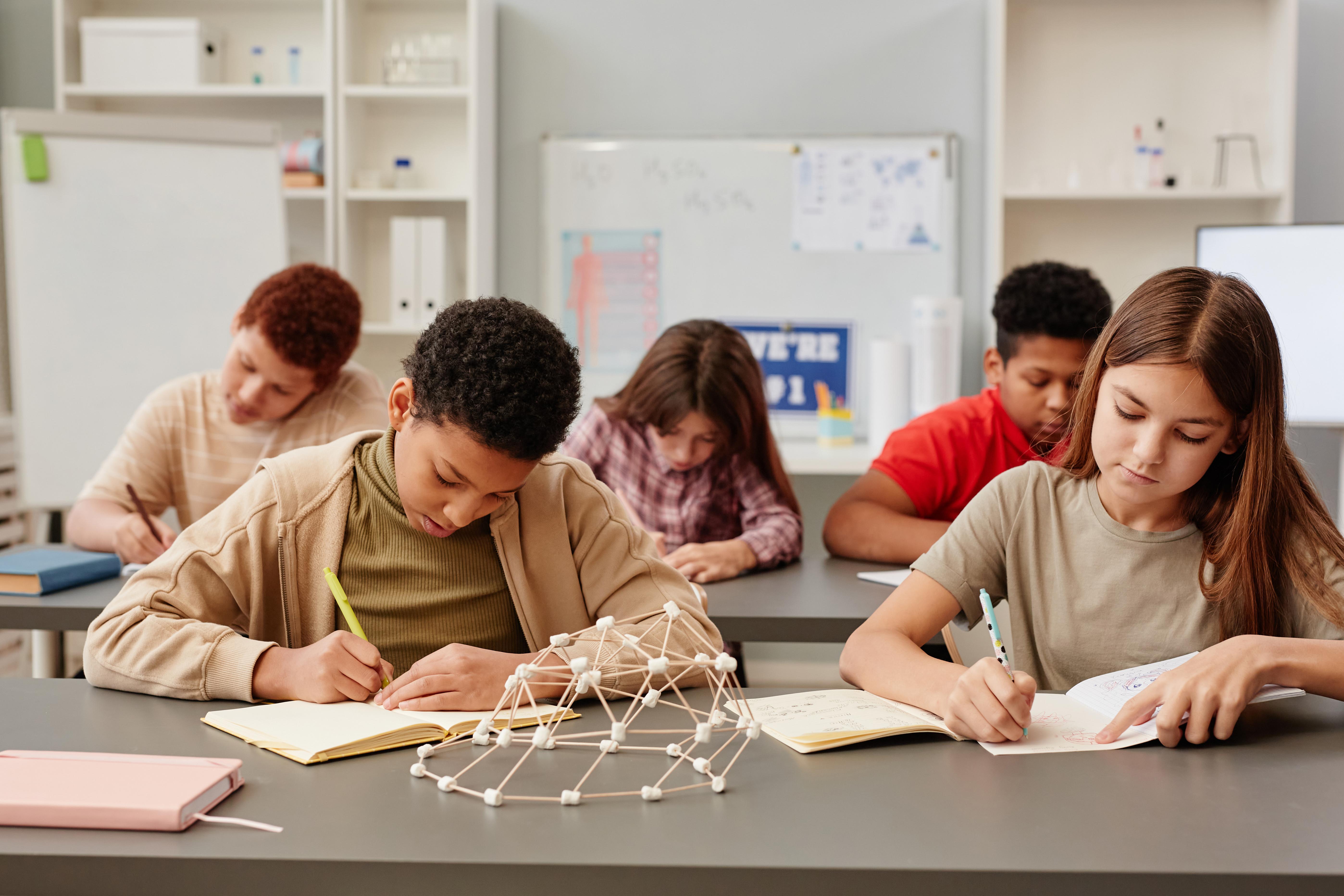 Children in classroom writing in composition books